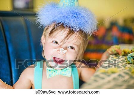 Stock Photography - Baby boy with messy birthday cake hands and nose at table. Fotosearch