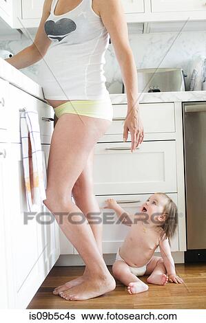 Baby girl on kitchen floor by pregnant mother View Large Photo Image Stock Photograph - Baby girl on kitchen floor by pregnant mother. Fotosearch
