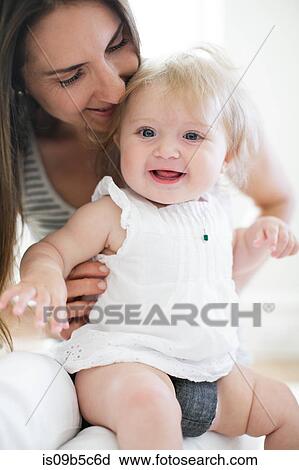 Baby girl sitting on mother's lap View Large Photo Image Stock Image - Baby girl sitting on mother's lap. Fotosearch