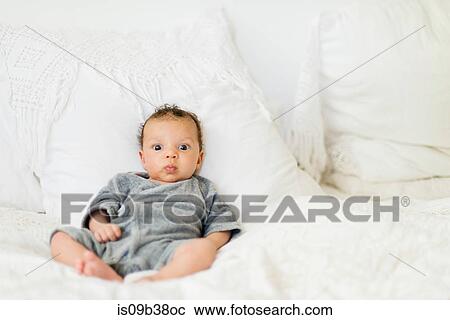 Stock Image - Baby sitting up on bed. Fotosearch