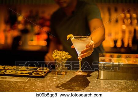 Stock Photo - Bar tender serving cocktail drink over bar. Fotosearch