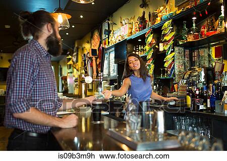 Barmaid handing change to male customer in public house View Large Photo Image Stock Image - Barmaid handing change to male customer in public house. Fotosearch