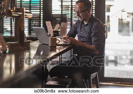 Barman reading smartphone texts at public house counter View Large Photo Image Stock Photo - Barman reading smartphone texts at public house counter. Fotosearch