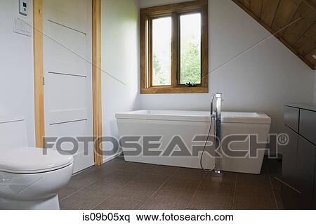 Bathroom with grey ceramic tile floor and white porcelain toilet and freestanding bathtub in cottage style log home, Quebec, Canada View Large Photo Image Stock Photography - Bathroom with grey ceramic tile floor and white porcelain toilet and freestanding bathtub in cottage style log home, Quebec, Canada. Fotosearch