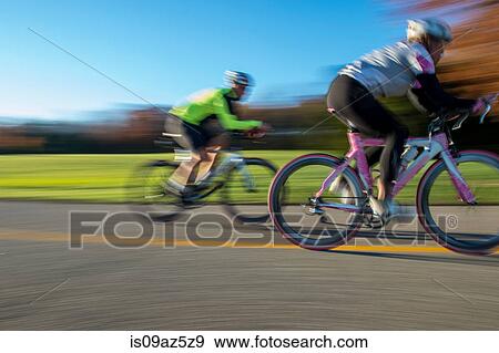 Stock Photo - Blurred motion side view of cyclists cycling. Fotosearch