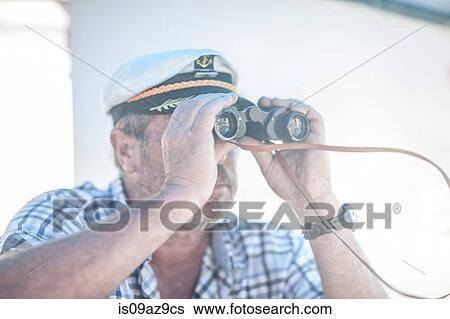 Stock Photograph - Boat captain looking through binoculars on boat, Cape Town, South Africa. Fotosearch