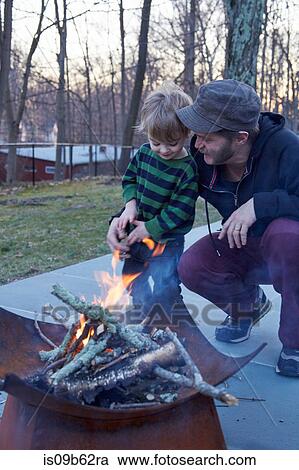 Boy and father tending fire in patio fire pit View Large Photo Image Stock Image - Boy and father tending fire in patio fire pit. Fotosearch