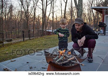 Boy and father tending fire in patio fire pit View Large Photo Image Stock Image - Boy and father tending fire in patio fire pit. Fotosearch
