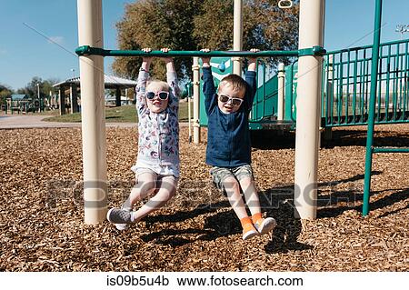 Boy and girl hanging from playground climbing frame View Large Photo Image Stock Image - Boy and girl hanging from playground climbing frame. Fotosearch