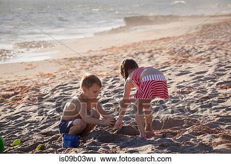 Boy and sister playing with sand on beach, Blowing Rocks Preserve, Jupiter Island, Florida, USA View Large Photo Image Stock Photograph - Boy and sister playing with sand on beach, Blowing Rocks Preserve, Jupiter Island, Florida, USA. Fotosearch