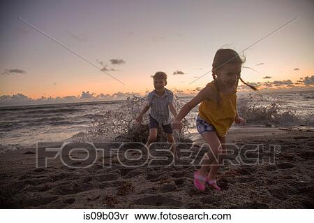 Boy and sister running away from splashing waves at sunrise, Blowing Rocks Preserve, Jupiter Island, Florida, USA View Large Photo Image Stock Photography - Boy and sister running away from splashing waves at sunrise, Blowing Rocks Preserve, Jupiter Island, Florida, USA. Fotosearch