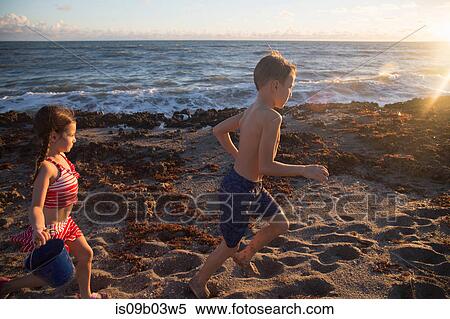Stock Photography - Boy and sister running on beach, Blowing Rocks Preserve, Jupiter Island, Florida, USA. Fotosearch