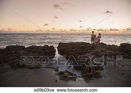 Boy and sisters looking out from rocks at sunrise, Blowing Rocks Preserve, Jupiter Island, Florida, USA View Large Photo Image Stock Photo - Boy and sisters looking out from rocks at sunrise, Blowing Rocks Preserve, Jupiter Island, Florida, USA. Fotosearch