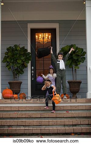 Boy and sisters trick or treating celebrating on porch View Large Photo Image Picture - Boy and sisters trick or treating celebrating on porch. Fotosearch