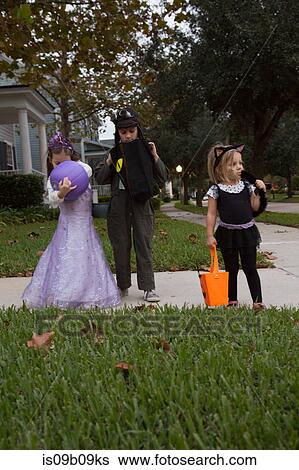 Boy and sisters trick or treating looking in bags on sidewalk View Large Photo Image Stock Photograph - Boy and sisters trick or treating looking in bags on sidewalk. Fotosearch