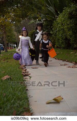 Boy and sisters trick or treating walking on sidewalk View Large Photo Image Stock Photography - Boy and sisters trick or treating walking on sidewalk. Fotosearch