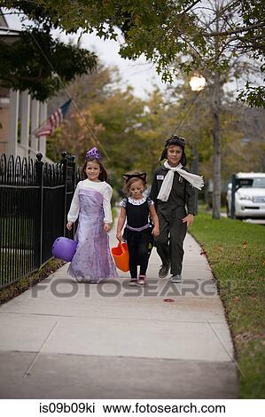 Boy and sisters walking along sidewalk trick or treating View Large Photo Image Stock Image - Boy and sisters walking along sidewalk trick or treating. Fotosearch