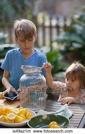 Boy and two young sister preparing lemon juice for lemonade at garden table View Large Photo Image Picture - Boy and two young sister preparing lemon juice for lemonade at garden table. Fotosearch