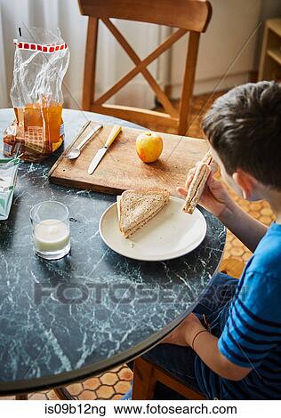 Boy at dining table eating sandwich View Large Photo Image Stock Image - Boy at dining table eating sandwich. Fotosearch