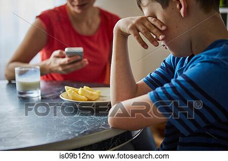 Boy at dining table, hand on eyes looking upset View Large Photo Image Picture - Boy at dining table, hand on eyes looking upset. Fotosearch