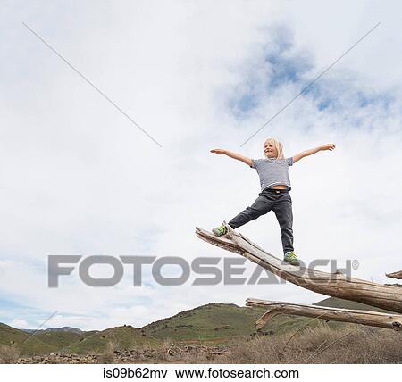 Boy balancing on end of tree trunk, sky in background View Large Photo Image Stock Photo - Boy balancing on end of tree trunk, sky in background. Fotosearch