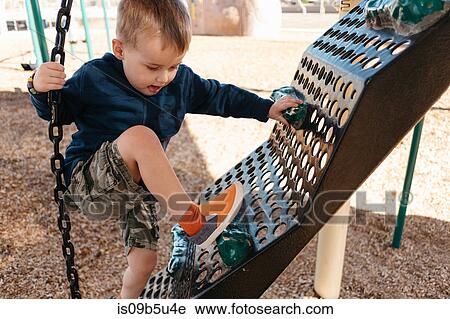 Stock Image - Boy climbing on playground climbing frame. Fotosearch