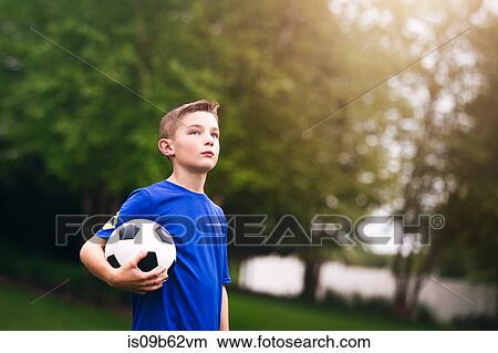 Boy holding soccer ball looking away View Large Photo Image Picture - Boy holding soccer ball looking away. Fotosearch