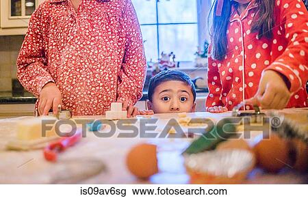 Boy in kitchen making cookies with sisters peeking over kitchen counter looking at camera View Large Photo Image Stock Image - Boy in kitchen making cookies with sisters peeking over kitchen counter looking at camera. Fotosearch