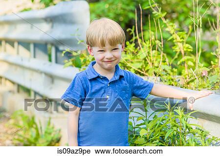 Boy leaning against crash barrier looking at camera smiling View Large Photo Image Stock Image - Boy leaning against crash barrier looking at camera smiling. Fotosearch