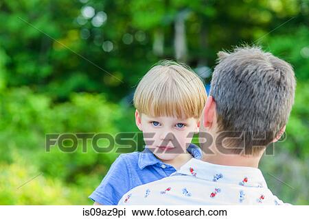 Boy looking at camera over fathers shoulders View Large Photo Image Stock Image - Boy looking at camera over fathers shoulders. Fotosearch