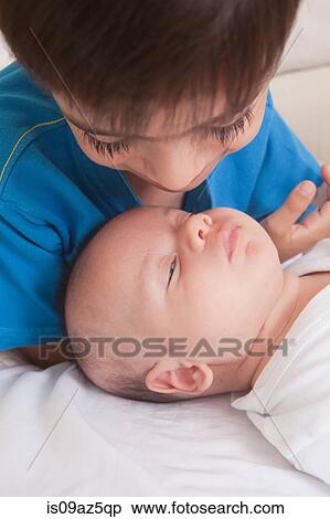 Stock Photography - Boy looking down at baby boy. Fotosearch