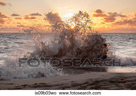 Boy playing in splashing waves at sunrise, Blowing Rocks Preserve, Jupiter Island, Florida, USA View Large Photo Image Picture - Boy playing in splashing waves at sunrise, Blowing Rocks Preserve, Jupiter Island, Florida, USA. Fotosearch