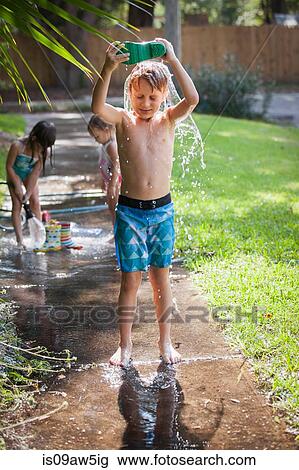 Boy pouring water from welly over head on sidewalk View Large Photo Image Stock Image - Boy pouring water from welly over head on sidewalk. Fotosearch