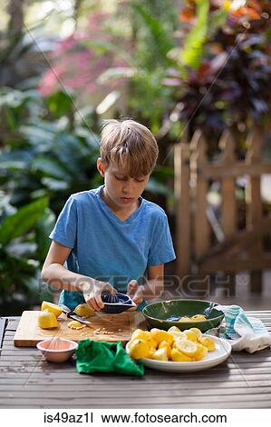 Boy preparing lemons for lemonade at garden table View Large Photo Image Stock Image - Boy preparing lemons for lemonade at garden table. Fotosearch