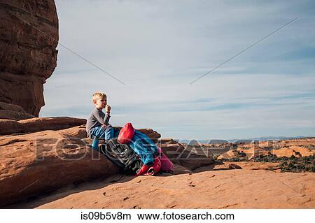 Boy sitting on rock in desert, eating snack, Moab, Utah, USA View Large Photo Image Picture - Boy sitting on rock in desert, eating snack, Moab, Utah, USA. Fotosearch