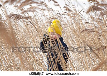 Boy standing in long grass, in snow covered landscape View Large Photo Image Stock Photo - Boy standing in long grass, in snow covered landscape. Fotosearch