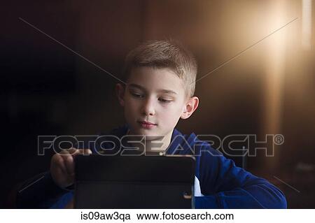 Stock Image - Boy using wireless digital tablet at home. Fotosearch