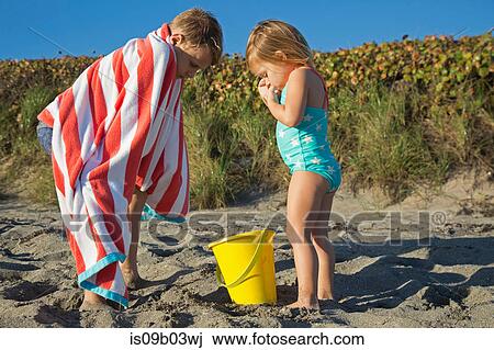 Boy wrapped in towel looking down at toy bucket with sister on beach, Blowing Rocks Preserve, Jupiter Island, Florida, USA View Large Photo Image Stock Image - Boy wrapped in towel looking down at toy bucket with sister on beach, Blowing Rocks Preserve, Jupiter Island, Florida, USA. Fotosearch