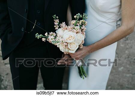 Bride and groom, arm in arm, bride holding bouquet of flowers, mid section View Large Photo Image Stock Photo - Bride and groom, arm in arm, bride holding bouquet of flowers, mid section. Fotosearch