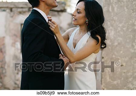 Bride and groom outdoors, bride straightening groom's neck tie View Large Photo Image Stock Photo - Bride and groom outdoors, bride straightening groom's neck tie. Fotosearch