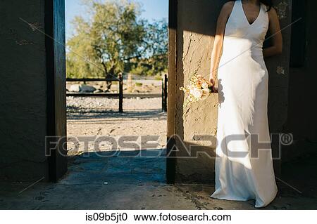 Bride leaning against wall, holding bouquet of flowers, low section View Large Photo Image Stock Image - Bride leaning against wall, holding bouquet of flowers, low section. Fotosearch