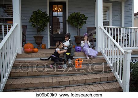Brother and sisters trick or treating on porch stairway View Large Photo Image Stock Photo - Brother and sisters trick or treating on porch stairway. Fotosearch