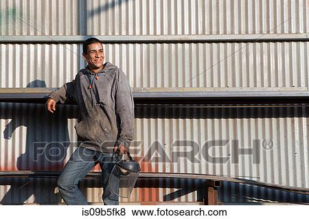 Builders leaning against corrugated building looking away smiling View Large Photo Image Stock Photo - Builders leaning against corrugated building looking away smiling. Fotosearch