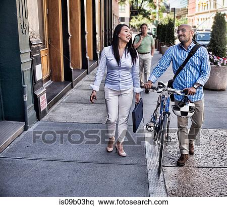 Business man and woman walking in street, man pushing bike, smiling View Large Photo Image Stock Photography - Business man and woman walking in street, man pushing bike, smiling. Fotosearch