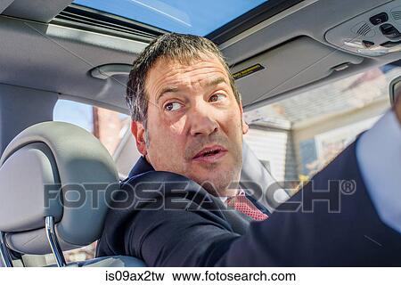 Business man in car looking over shoulder View Large Photo Image Stock Photo - Business man in car looking over shoulder. Fotosearch