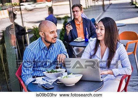 Business people sitting outside cafe, using laptop View Large Photo Image Stock Photo - Business people sitting outside cafe, using laptop. Fotosearch