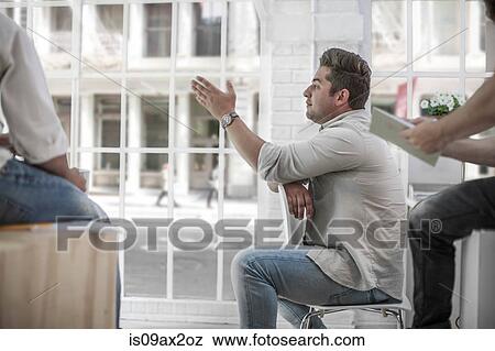 Businessman and colleagues brainstorming in loft office View Large Photo Image Stock Photo - Businessman and colleagues brainstorming in loft office. Fotosearch
