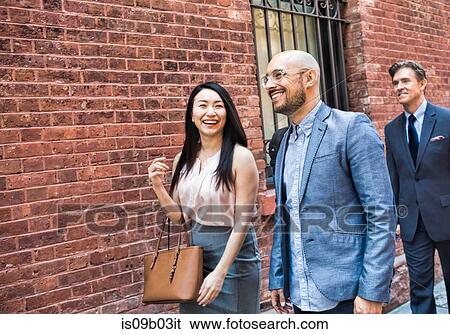 Businessman and woman walking together in street, smiling View Large Photo Image Stock Photograph - Businessman and woman walking together in street, smiling. Fotosearch