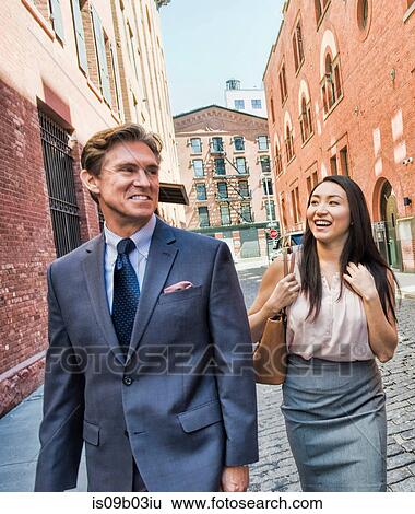 Businessman and woman walking together in street, smiling View Large Photo Image Stock Photograph - Businessman and woman walking together in street, smiling. Fotosearch