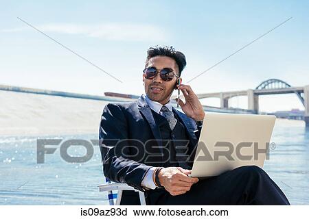 Businessman in deckchair on Los Angeles river using smartphone and laptop, California, USA View Large Photo Image Stock Image - Businessman in deckchair on Los Angeles river using smartphone and laptop, California, USA. Fotosearch